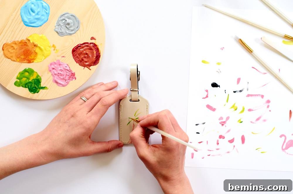 A woman wearing a wedding ring painting a luggage tag with an array of colors on her palette. Enjoy the creative process of painting your personalized designs onto the leather luggage tags.