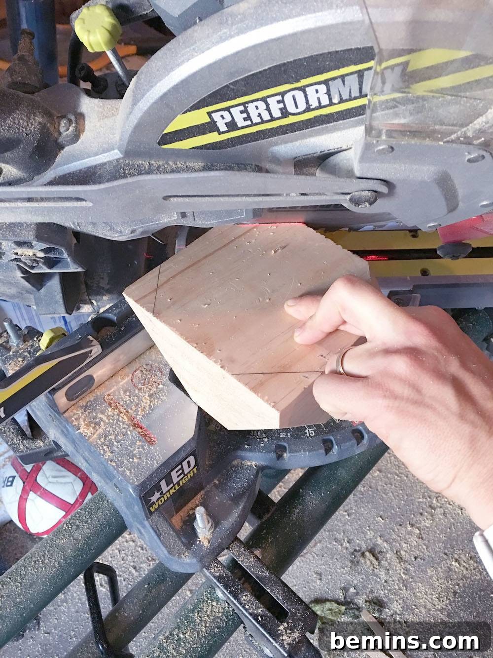 Cutting a small piece of wood with a silver power tool in a workshop.