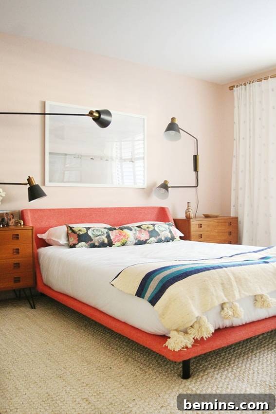 A made bed with a blue striped throw blanket on an orange bed frame with four spotlights above it.