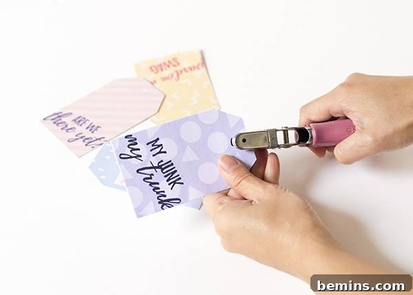 Printable cheeky luggage tags showing using a hole punch