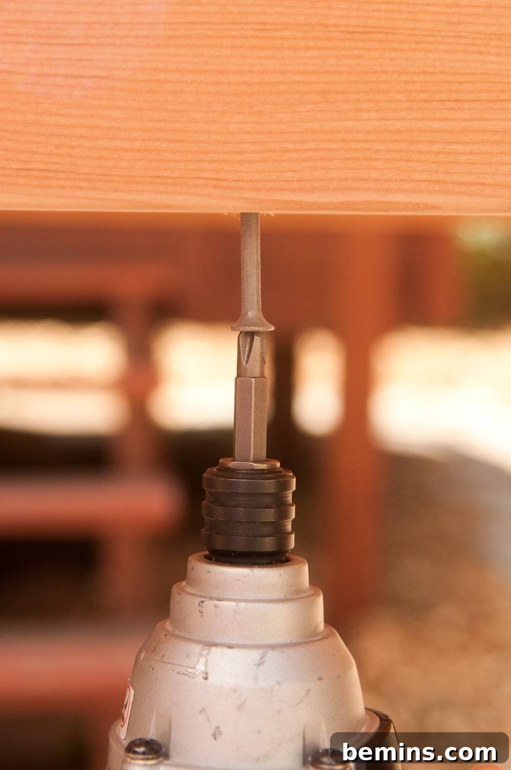 White screwdriver drilling a nail into a piece of wood to make a workbench.