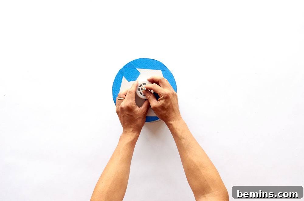 A man applies paint in the middle of a blue taped circle