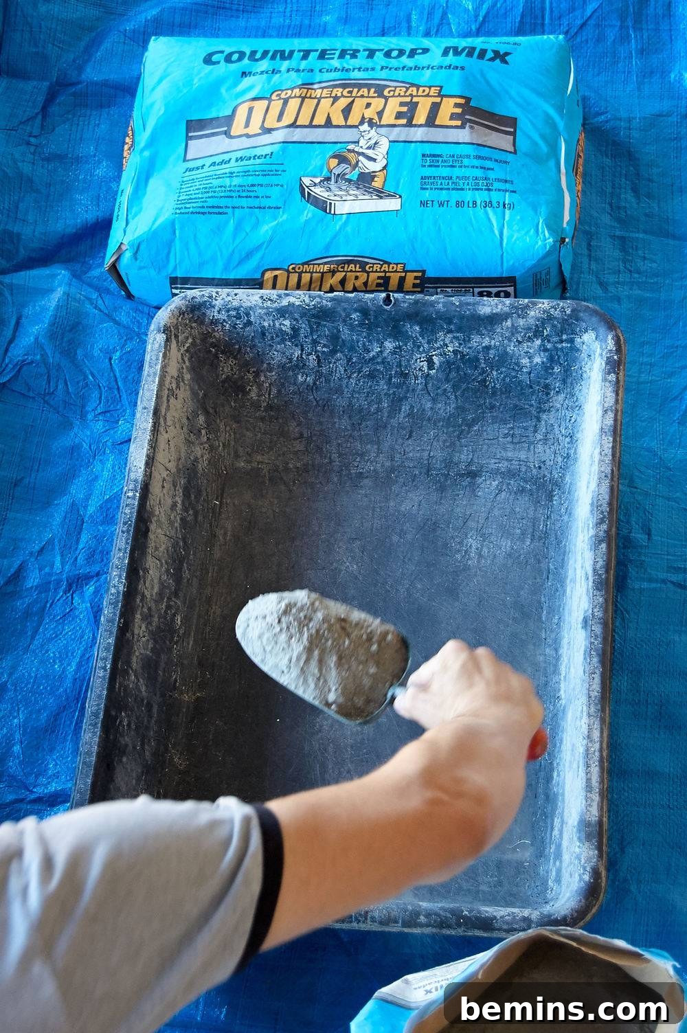 A person puts a scoop of Quickpete into a pan.
