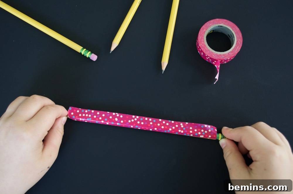 Kid-Friendly DIY: Personalized Pencil Pouches for School 7 A person is stretching out a piece of pink speckled tape: Preparing to wrap the pencil