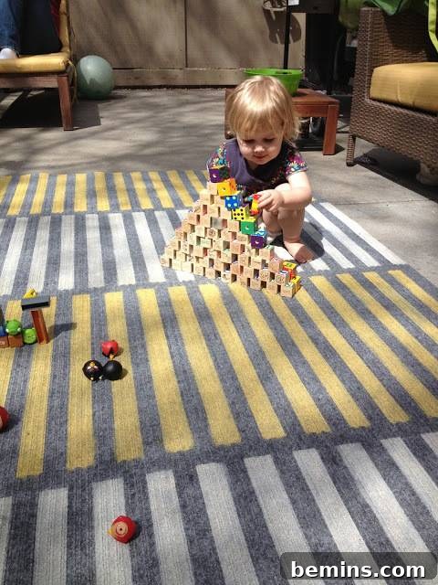 A toddler sitting playfully among colorful and stylish rugs.