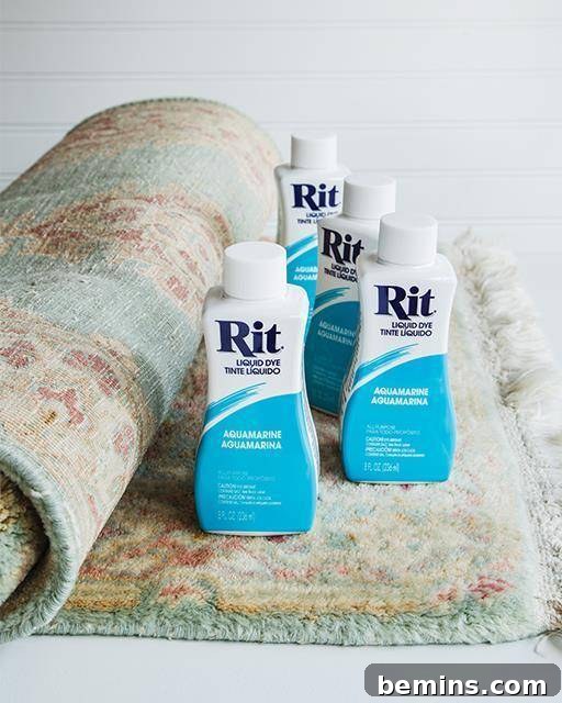 Four bottles of Rit dye sitting on top of a partially rolled rug.
