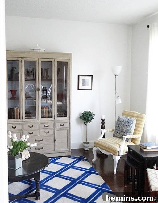 A beautifully decorated sitting room featuring a blue and white lattice patterned carpet and a stylish grey sideboard.