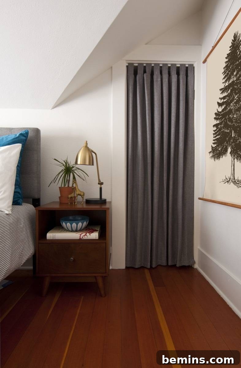 A closet with curtain bedside table bed and DIY framed wall art