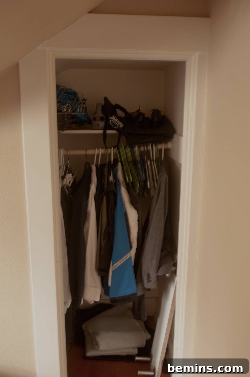 A closet with a small assortment of organized clothes.