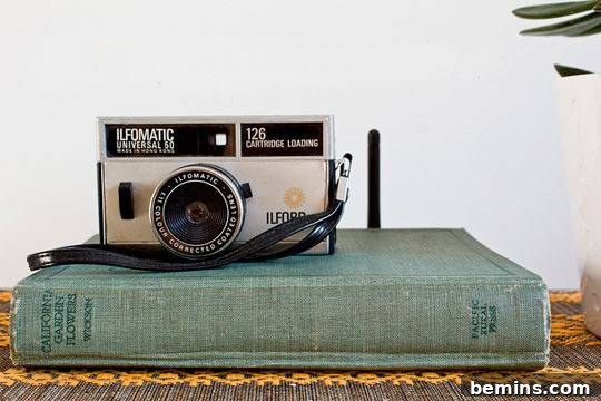 An antique Ilfomatic camera sitting atop a green book.