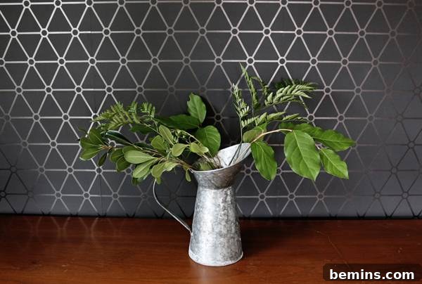 Arranging greenery in a vase to create the initial shape of the bouquet.
