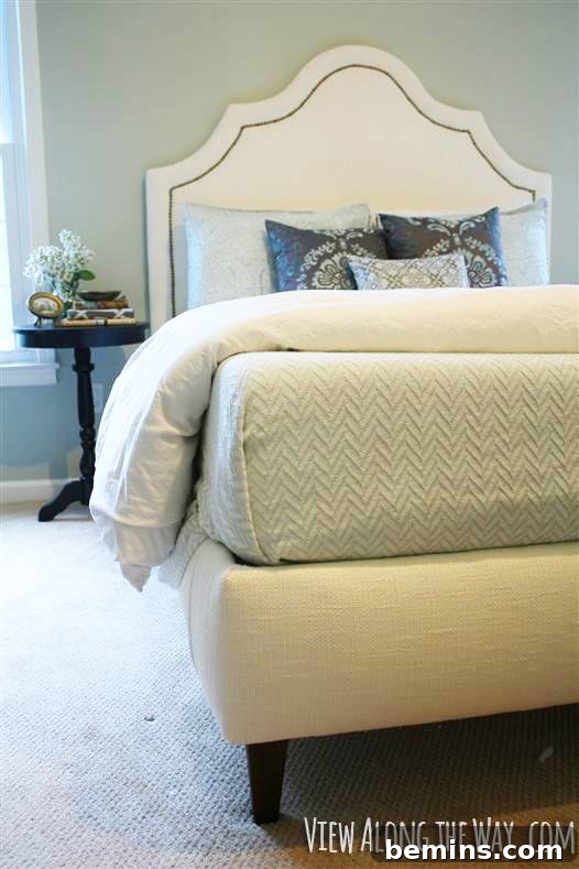 A bed featuring a white comforter and a nightstand nearby.