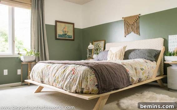 A made bed on a light-colored wooden frame with a white sheepskin rug and a tan macrame hanging on the green and white wall above the bed.