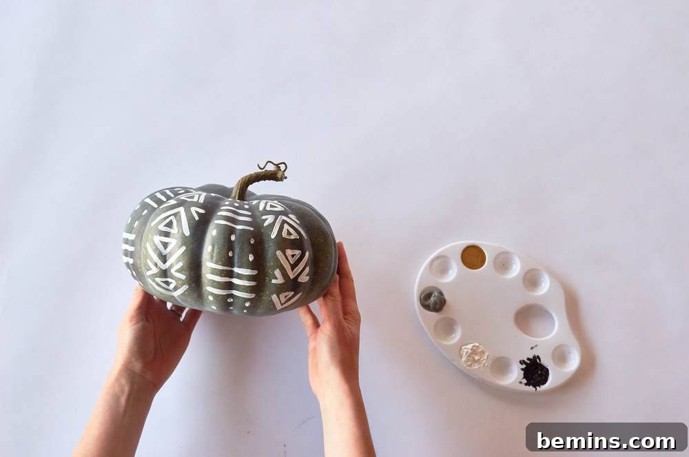 Man holding a pumpkin with painted on it.