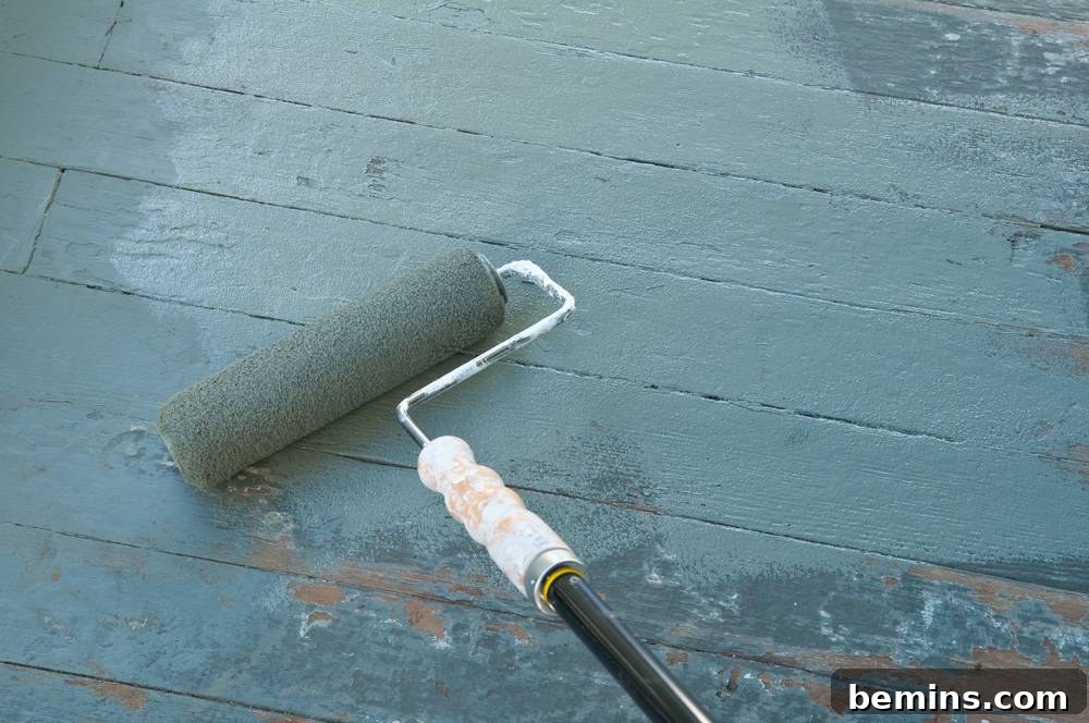 A person rolling gray paint onto a wooden surface of the porch.