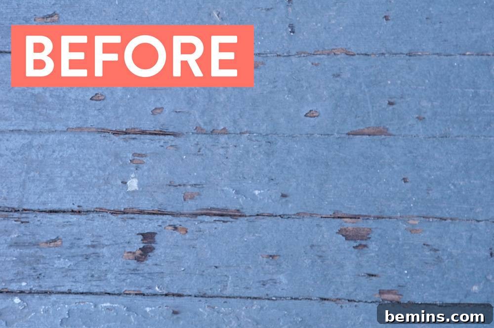 Close-up of cracked and chipped blue paint on a wooden porch surface.
