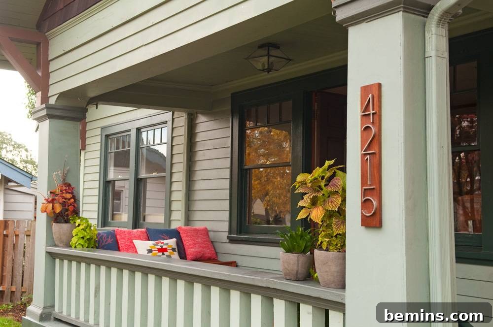 Painted sage front porch rails and columns with plants.