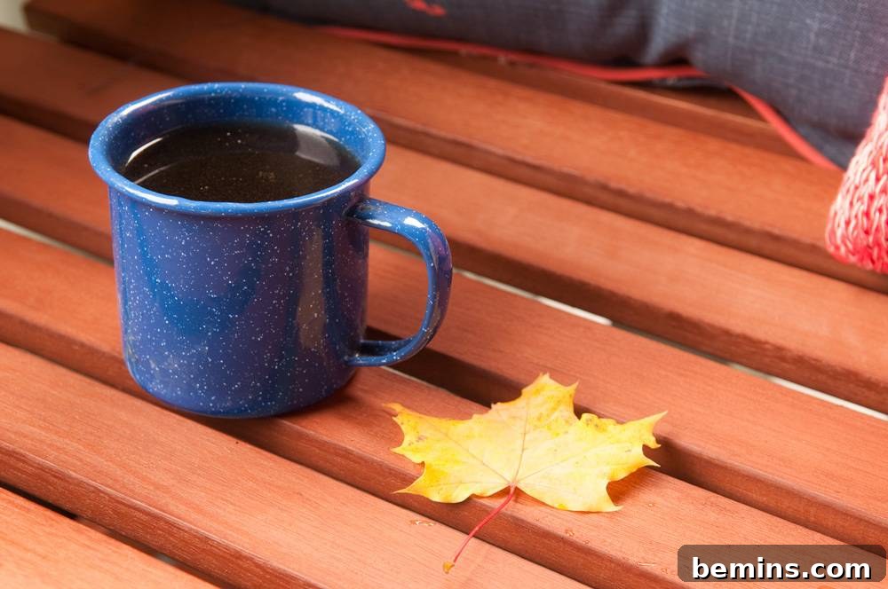 Coffee in a blue mug near a leaf, capturing a cozy moment on the porch.