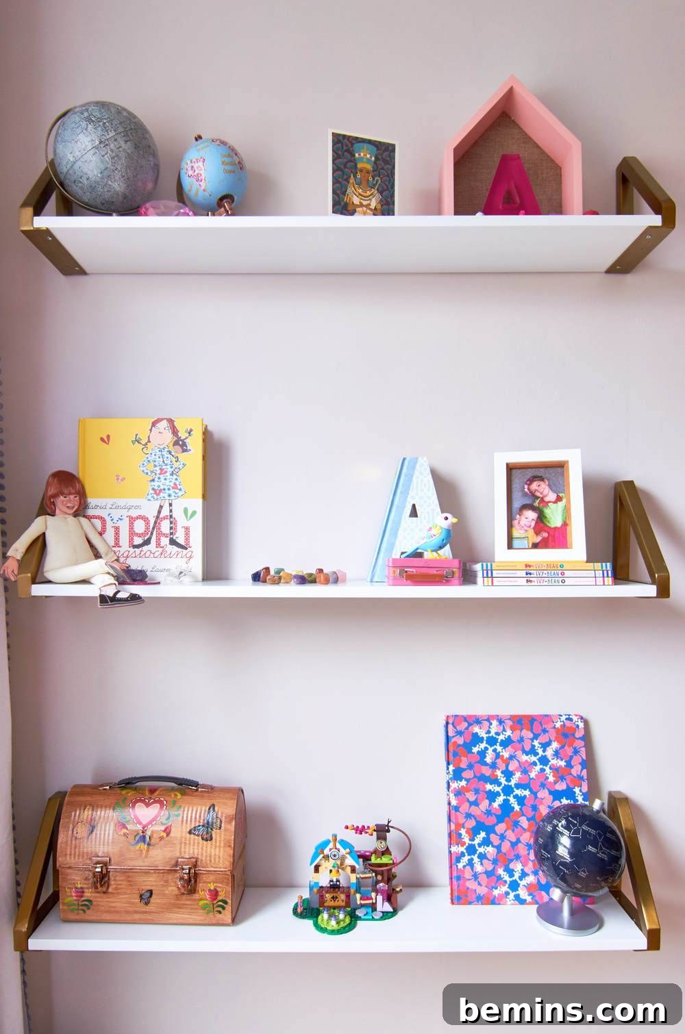 After: Three white floating shelves with a glove, a pink house, a yellow book, a brown lunch pail and a pink and blue notebook on them.