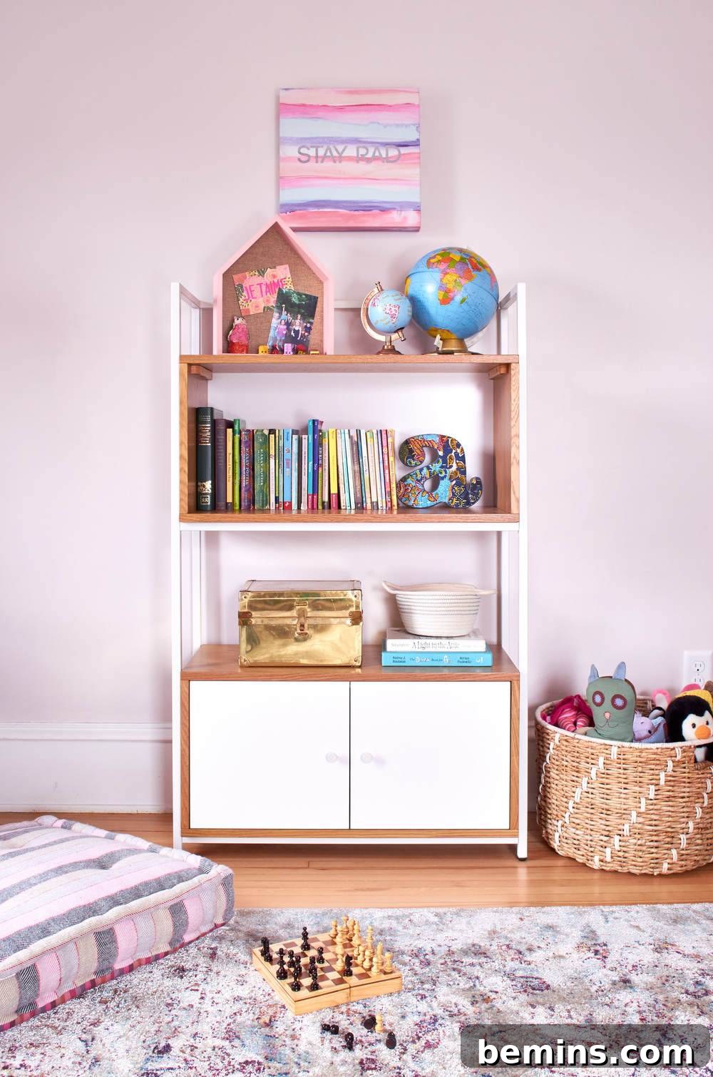 White bookcase in Ayla's room, accented with pink and colorful decorative items.