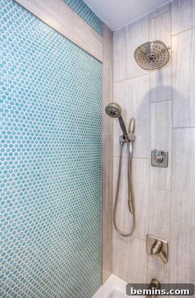 Elegant shower design featuring blue mosaic tiles and stainless steel fixtures.